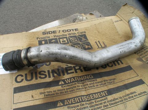 2000 Ford Excursion - A metal intercooler pipe with rubber connectors and hose clamps is shown on a cardboard box with handling warnings.