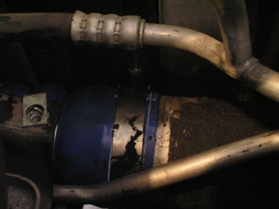 Underbody blue-banded fuel filter with metal lines and bracket, dirty and corroded.