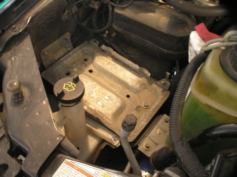2000 Ford Excursion - Close-up of an empty battery tray and coolant reservoir in a vehicle's engine bay.