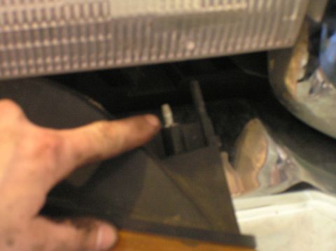 2000 Ford Excursion - Close-up of a finger indicating a plastic clip, likely part of a vehicle's lighting assembly.
