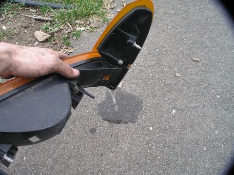 2000 Ford Excursion - Detached car turn signal assembly being held over asphalt.