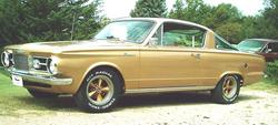 1964 Plymouth Barracuda - A gold 1964 Plymouth Barracuda is parked on a gravel surface with trees in the background.