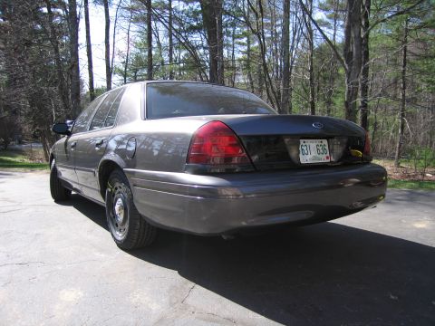 1991 Ford LTD Crown Victoria - This dark gray sedan, likely a Ford Crown Victoria from the 2003-2011 generation, is seen from the rear.
