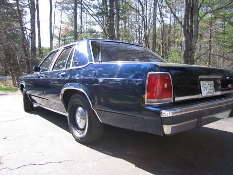 1991 Ford LTD Crown Victoria - Rear view of a dark blue sedan, possibly a Ford LTD, with a license plate reading 160 7339.