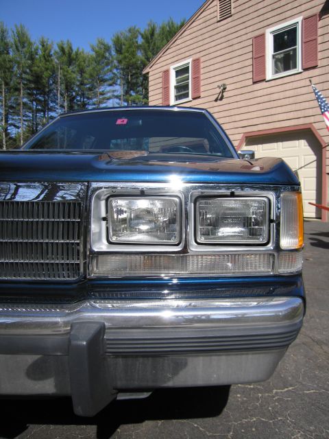 1991 Ford LTD Crown Victoria - The front of a blue sedan is visible, with a chrome bumper and grille.