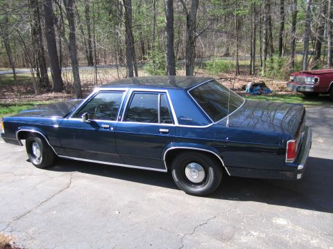 1991 Ford LTD Crown Victoria - Side view of a 1991 Ford Crown Victoria LTD sedan parked outdoors. Another vehicle is partially visible.