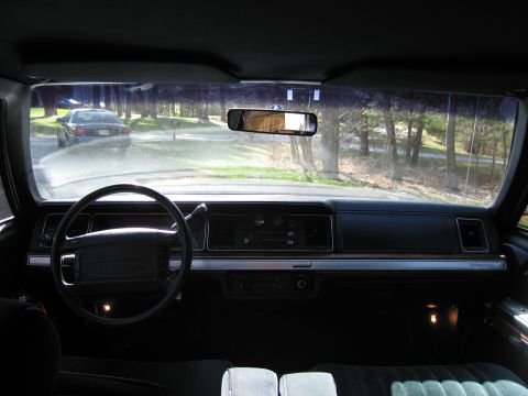 1991 Ford LTD Crown Victoria - Interior view of a sedan, with another car visible through the windshield on a tree-lined road.
