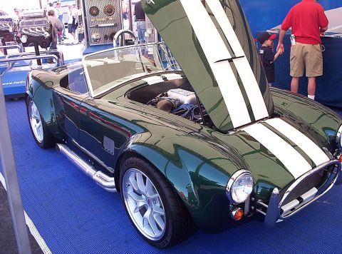 1995 Ford Bronco - Green AC Cobra replica with white stripes and hood open, displayed on a blue floor.
