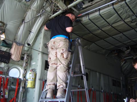 1988 Ford Bronco - A person on a ladder works inside the cargo bay of an aircraft.