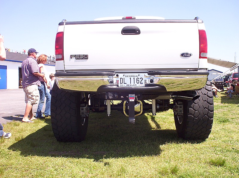 Rear view of a lifted white Ford F-Series truck with large tires and a chrome bumper. Georgia license plate DL 1162 is visible