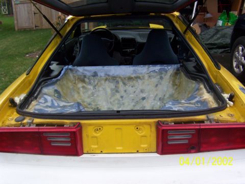 1994 Ford Probe - The interior of a yellow sports car shows stripped cargo area and two dark seats.