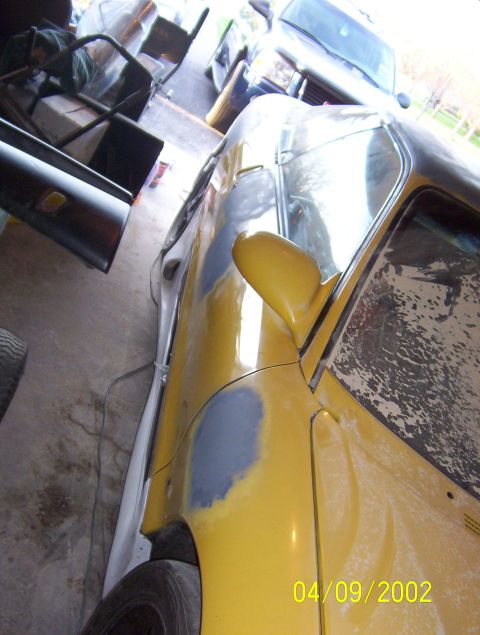 1994 Ford Probe - A yellow car is in a garage, showing signs of body repair work. Another vehicle is visible in the background.