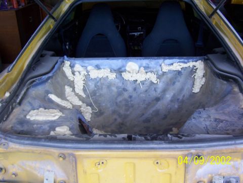 1994 Ford Probe - The interior of a yellow car shows exposed foam insulation in the trunk area, with a date stamp of 04/09/2002.