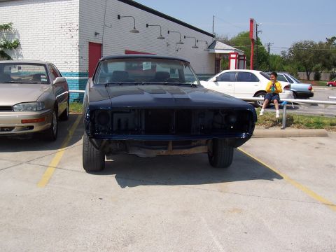 1969 Ford Ranchero - A dark blue pickup truck is parked in a lot, missing its front grille and headlights.