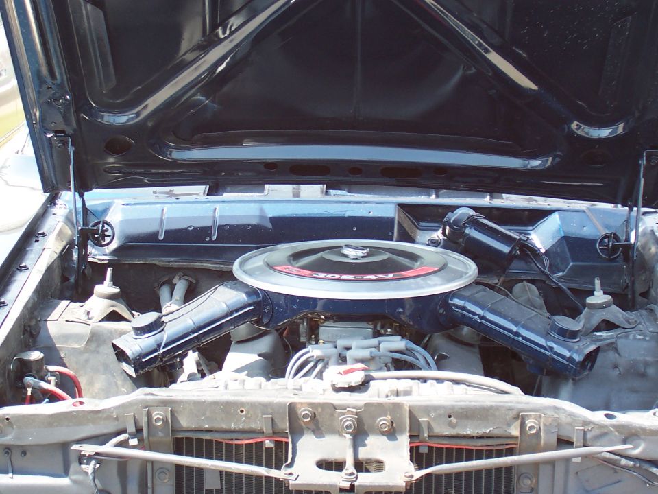 Engine bay of classic Ford with 302 V8, round air cleaner and blue valve covers