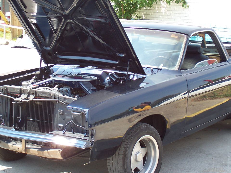 Dark Ford Ranchero with hood up, front end disassembled, engine and radiator exposed