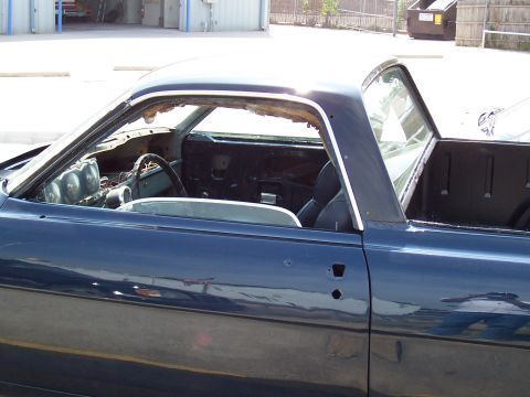 1969 Ford Ranchero - A dark blue 1969 Ford Ranchero is seen from the side, with its interior exposed and missing glass.