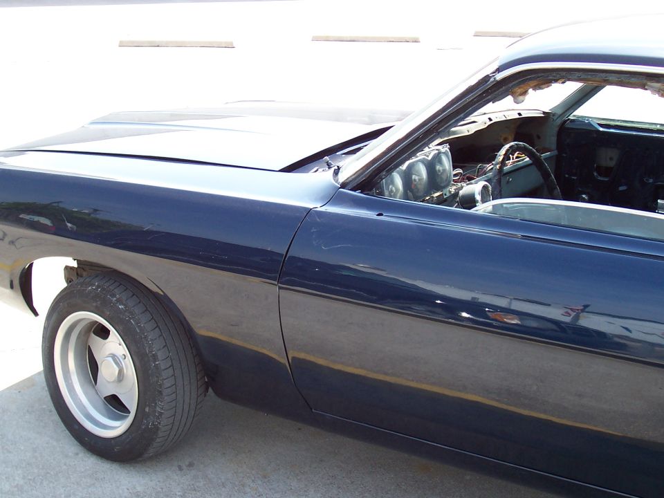 Dark blue project car in restoration with stripped interior and silver five-spoke wheels
