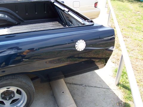 1969 Ford Ranchero - Close-up of a dark blue pickup truck's bed and rear quarter panel, with another vehicle visible in the background.