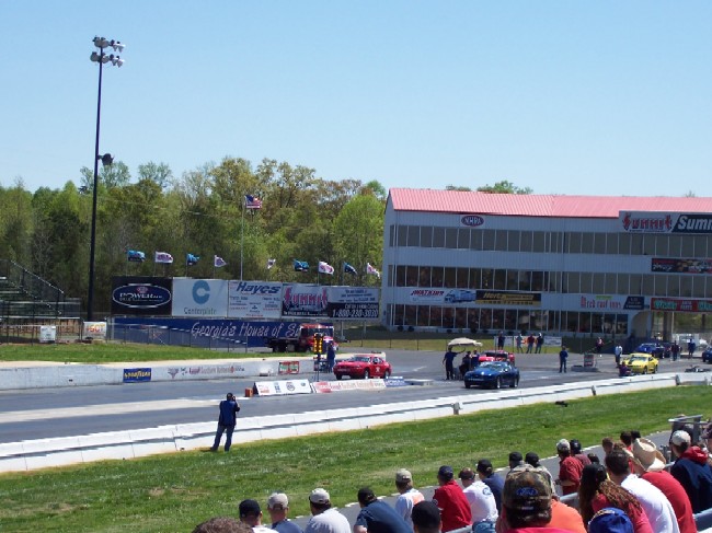 Drag strip with red and blue cars at the starting line