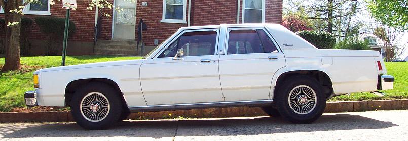 White sedan parked curbside, side view