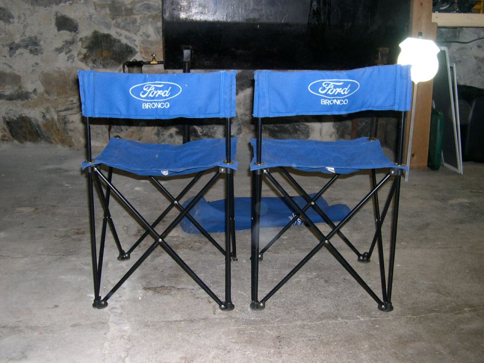 Two blue folding chairs with Ford Bronco logos on them, set up indoors