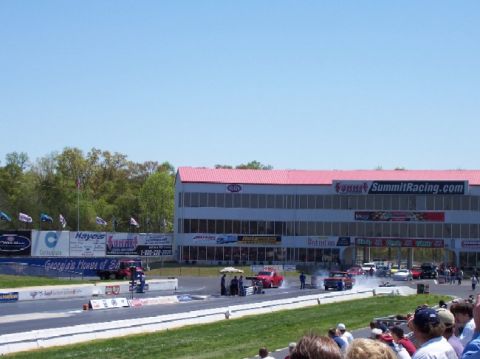 1978 Ford F-250 - Cars race down a drag strip in front of a building with a red roof and Summit Racing signage.