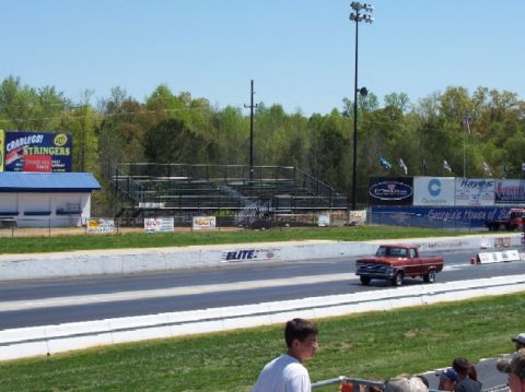 1978 Ford F-250 - A red pickup truck is seen on a drag strip under a clear blue sky.