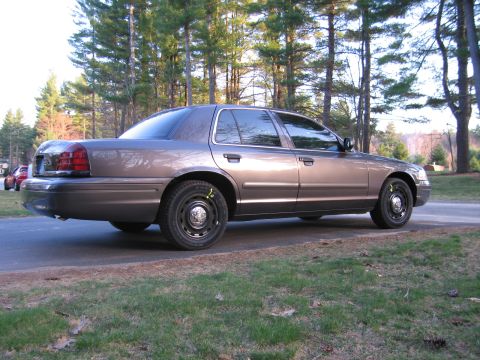 1991 Ford LTD Crown Victoria - This brown sedan, seen from the rear quarter, appears to be a Ford Crown Victoria from the 2003-2011 model years.