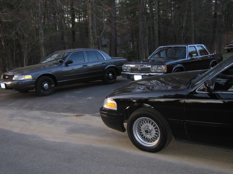 1991 Ford LTD Crown Victoria - Multiple Ford Crown Victorias are parked outdoors, with a focus on the front-right quarter of a black model.