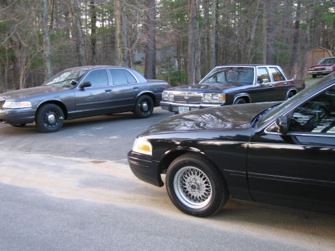 1991 Ford LTD Crown Victoria - Three Ford Crown Victoria sedans are parked on an asphalt surface with trees in the background.