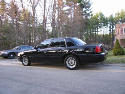 1991 Ford LTD Crown Victoria - A black sedan is parked on the side of the road with a grey sedan behind it.