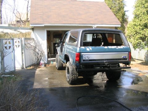 1986 Ford Bronco - Rear view of a blue 1986 Ford Bronco, modified with a snorkel and custom bumper, parked in a driveway.