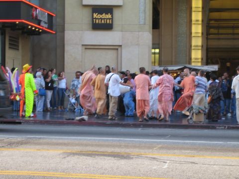 1968 Ford Mustang - A group of people in traditional Indian attire are dancing on the sidewalk in front of the Kodak Theatre.