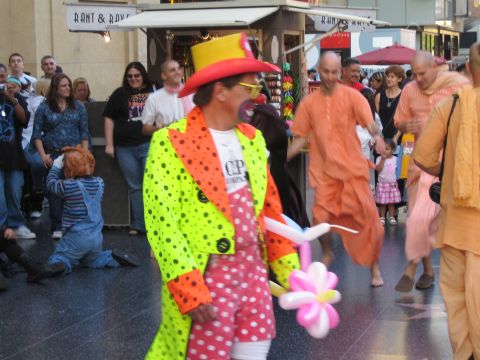 1968 Ford Mustang - A street performer in a clown costume is seen on a sidewalk with onlookers and a group of people in orange robes.