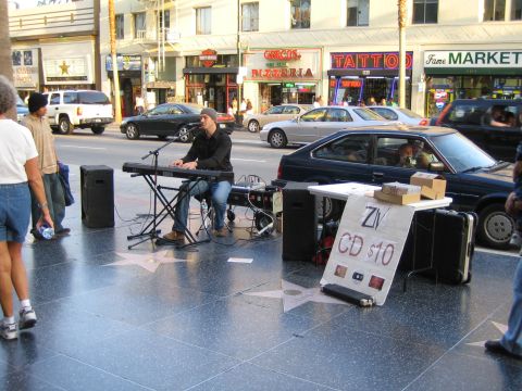 1968 Ford Mustang - A street performer plays a keyboard on the Hollywood Walk of Fame, with a sign advertising "ZIV CD $10" visible.