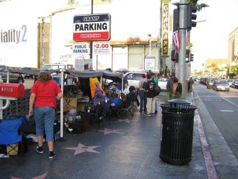 1968 Ford Mustang - People gather on the Hollywood Walk of Fame, with a parking sign and traffic visible on the street.