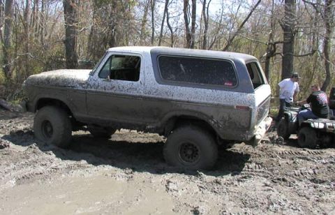 1988 Ford Bronco - This SUV is stuck in the mud while two people on ATVs watch.