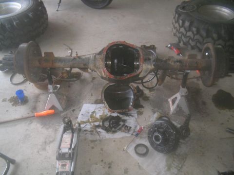 1983 Ford F-250 - Disassembled rear axle assembly with gears and tools scattered around on a concrete floor.