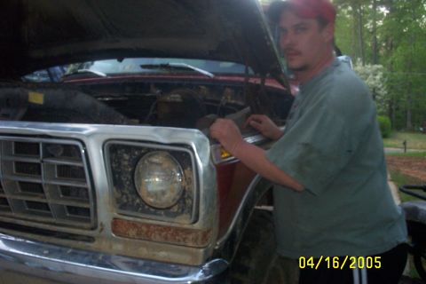 1979 Ford F-150 - Man works on the engine of a 1979 Ford F-150 truck with the hood open.