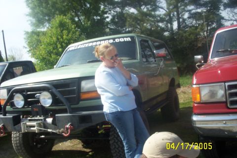 1979 Ford F-150 - A green SUV with a winch and bull bar is parked next to a red truck, with text on the windshield reading FULLSIZEBRONCO.COM.