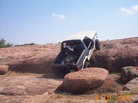 1986 Ford Bronco - A Ford Bronco navigates a rocky terrain on a sunny day.
