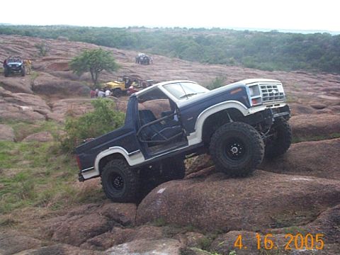 1986 Ford Bronco - 1986 Ford Bronco navigating rocky terrain with other vehicles present.