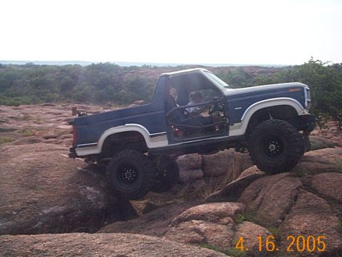 1986 Ford Bronco - This modified Ford Bronco navigates a rocky terrain with its doors removed and a roll cage installed.