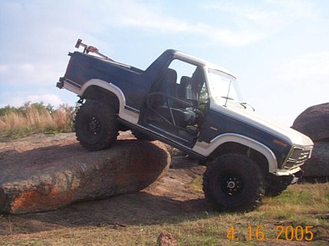 1986 Ford Bronco - Ford Bronco navigating rocky terrain with its doors open.
