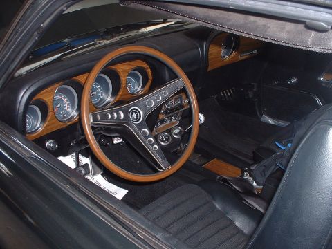 1999 Ford Crown Victoria - The interior of a 1969 Ford Mustang features a wood grain dashboard and a classic wood rim steering wheel.