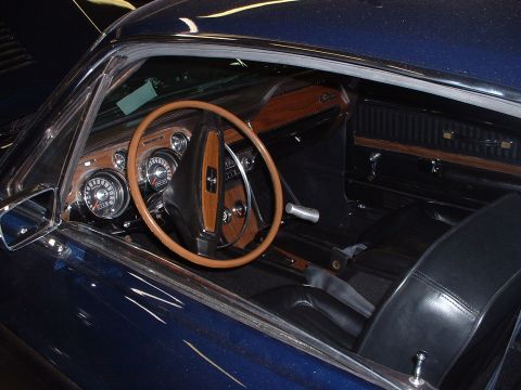 1999 Ford Crown Victoria - Interior view of a classic dark blue car, wood grain accents on the dashboard and a wood-rimmed steering wheel, likely a 1968 Mustang.