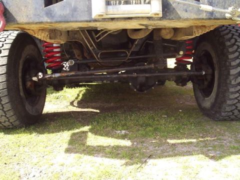 1989 Ford Bronco - The undercarriage of a modified off-road vehicle is shown, with a focus on its suspension and drivetrain components.
