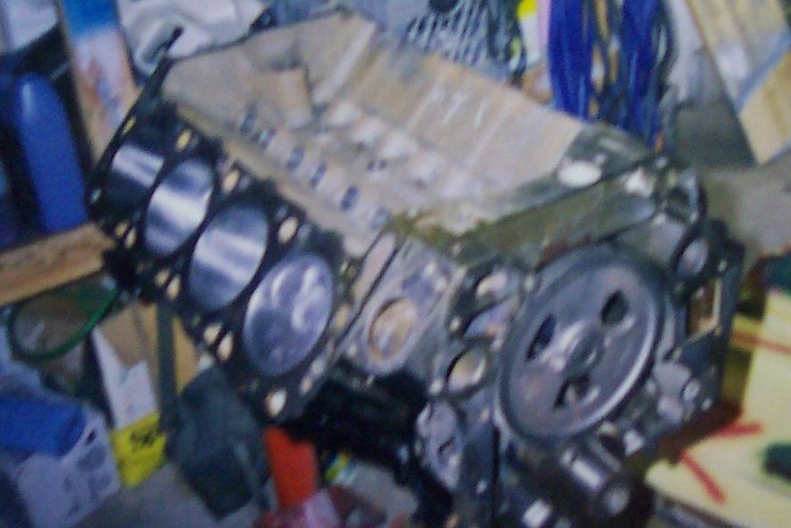 Engine block with cylinders visible, sitting on a stand. Some parts are covered with tape