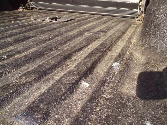 Textured spray-in bedliner over the ribbed floor of a pickup bed looking toward the tailgate